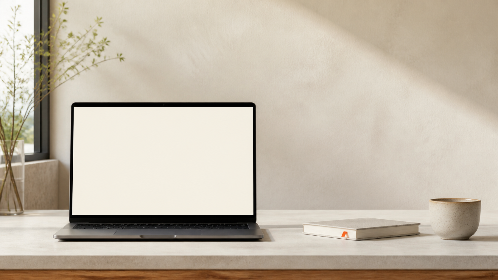 A laptop with a quiet blank screen on a warm, sunlit desk.
